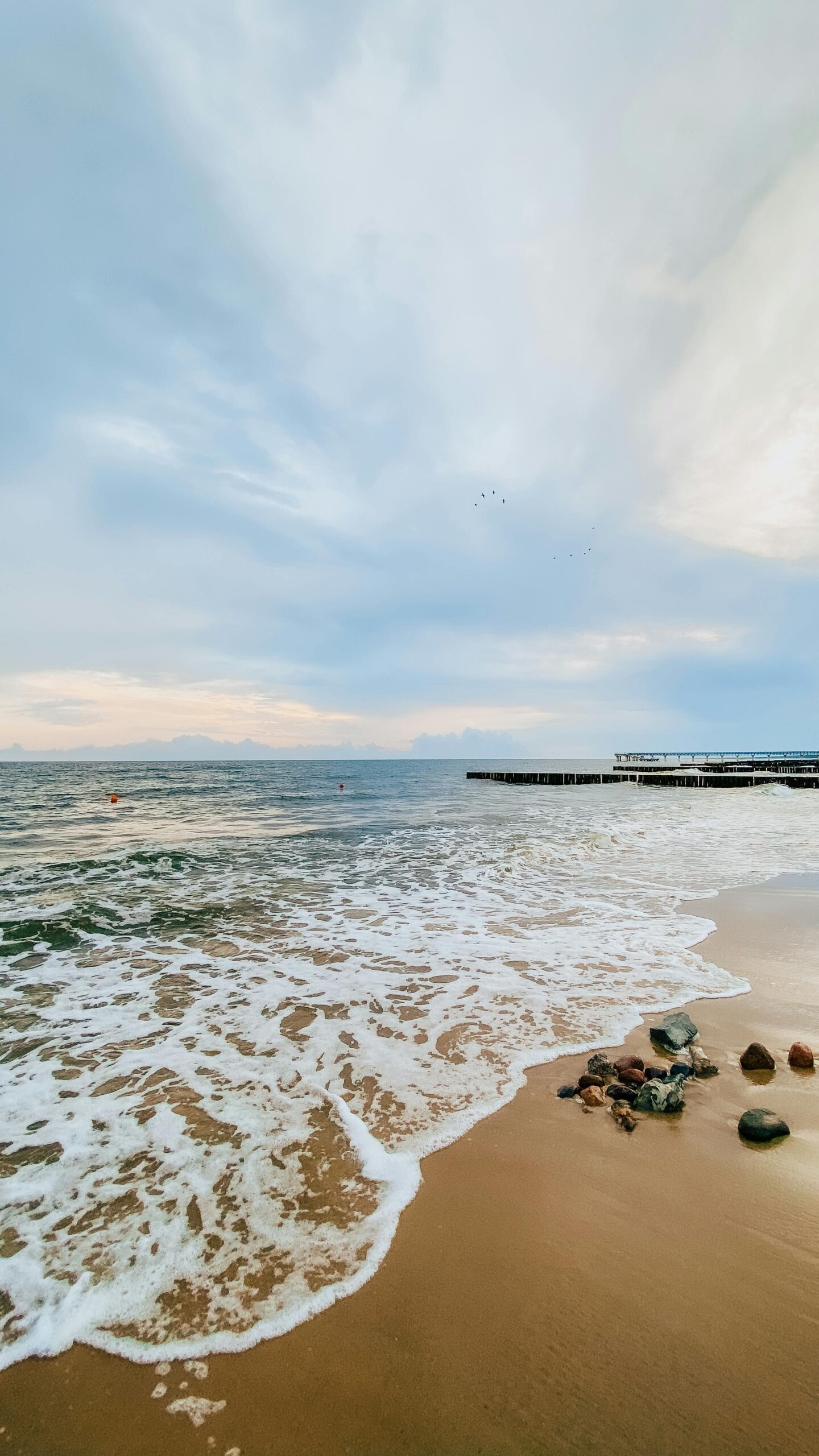 Beautiful seaside view of a sandy beach with gentle waves and a calm sunset sky.